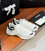 White Chanel sneakers with black accents, lace-up front, and cushioned sole