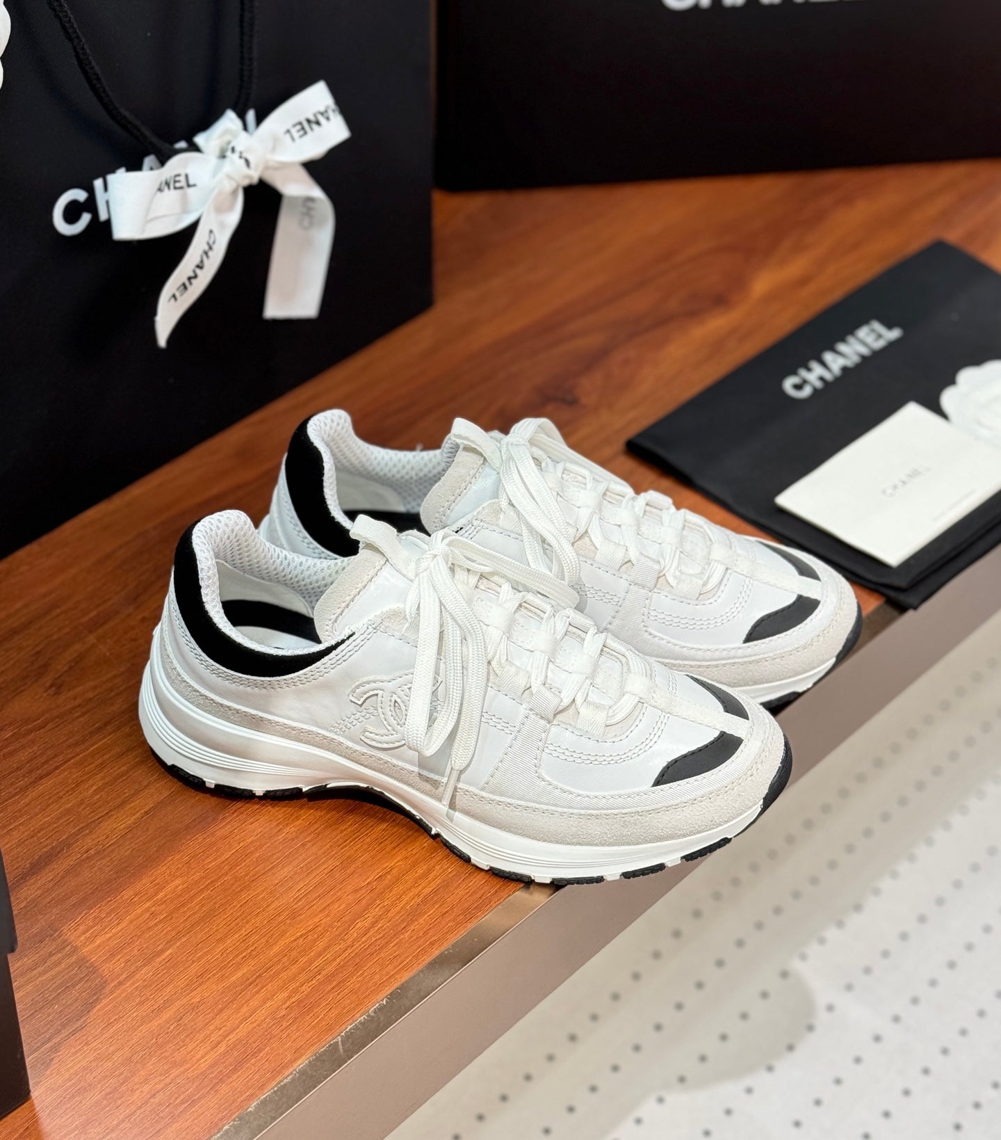 White Chanel sneakers with black accents, lace-up front, and cushioned sole