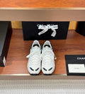 Pair of white Chanel unisex sneakers with black trim and lace-up design