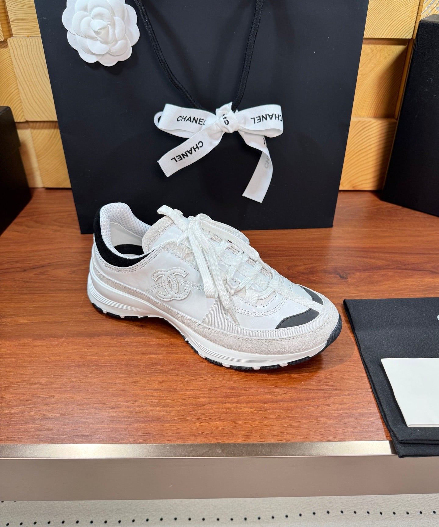 White Chanel sneaker with black-trim collar, lace-up closure, and chunky sole