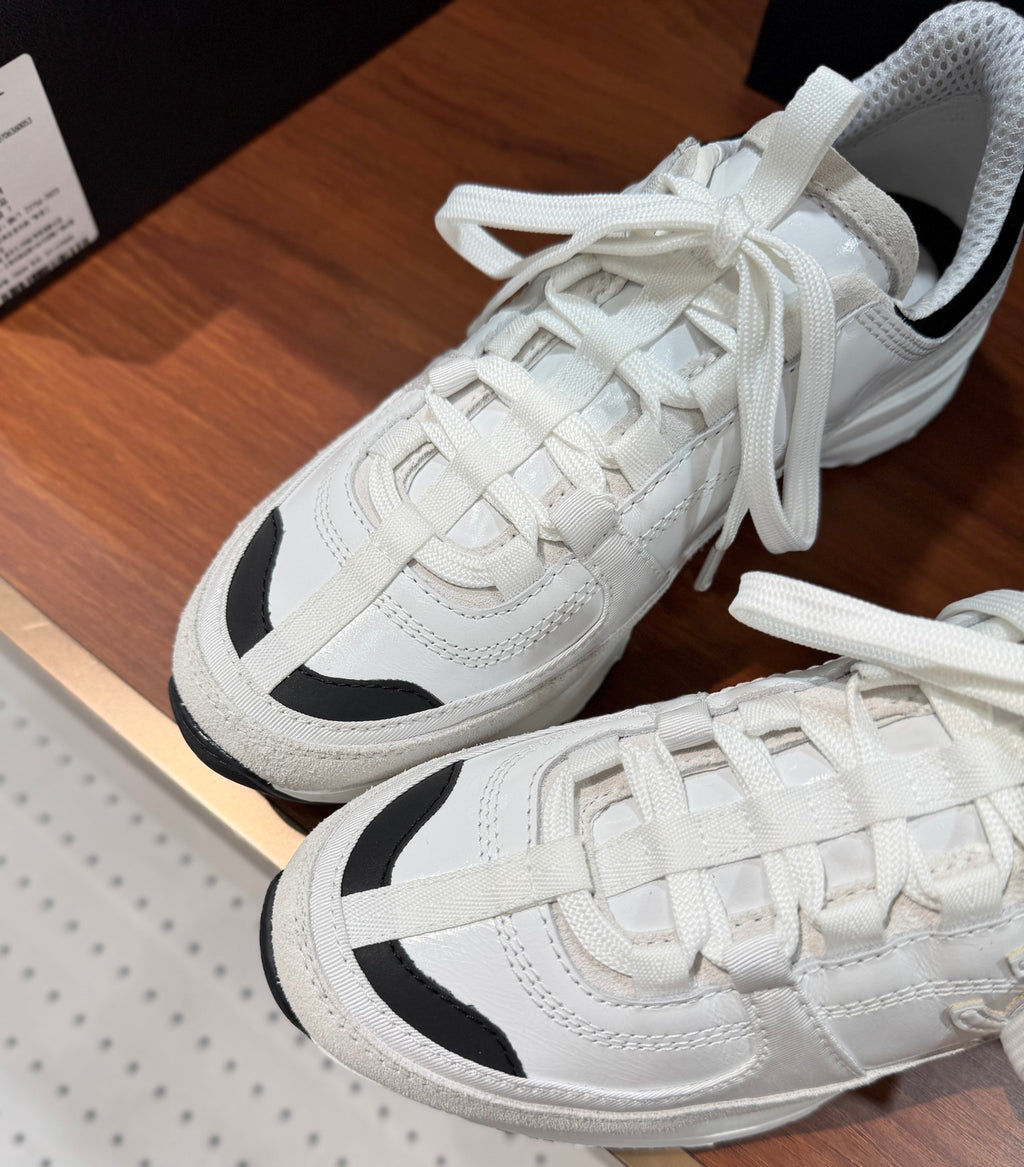 Close-up of white Chanel sneakers with woven laces and black side panels