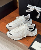 White Chanel sneakers with black collar lining and thick striped rubber sole