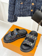 Black Louis Vuitton slide sandals with multicolor monogram print, pair shown on box