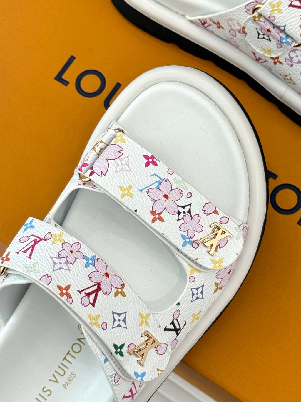 Louis Vuitton ladies luxury shoes, close-up of white slide strap with multicolor floral logo print