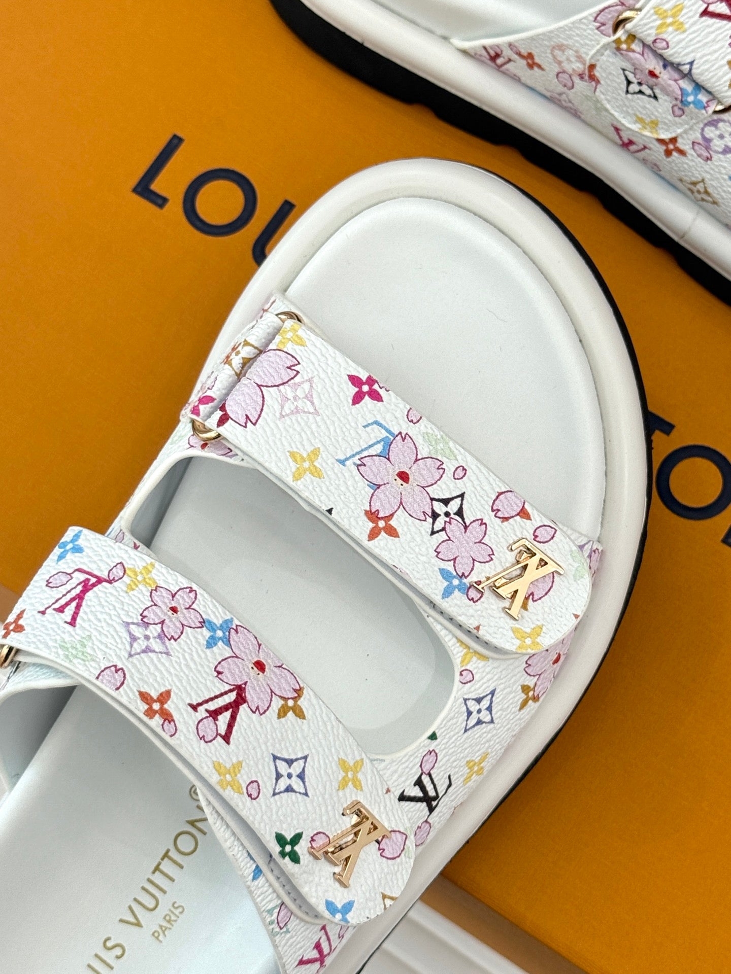 Louis Vuitton ladies luxury shoes, close-up of white slide strap with multicolor floral logo print