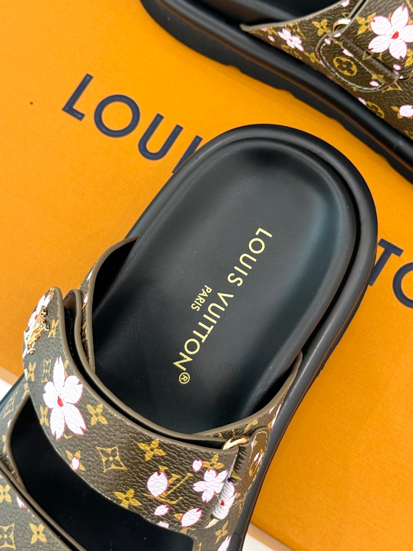 Ladies slide sandals close-up showing “Louis Vuitton” on black footbed