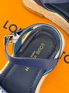 Blue espadrille sandal with yellow text on inner lining and adjustable buckle strap