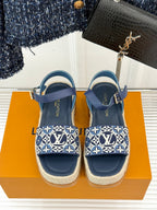 Blue slip-on espadrille sandals with monogram-style straps and ankle strap