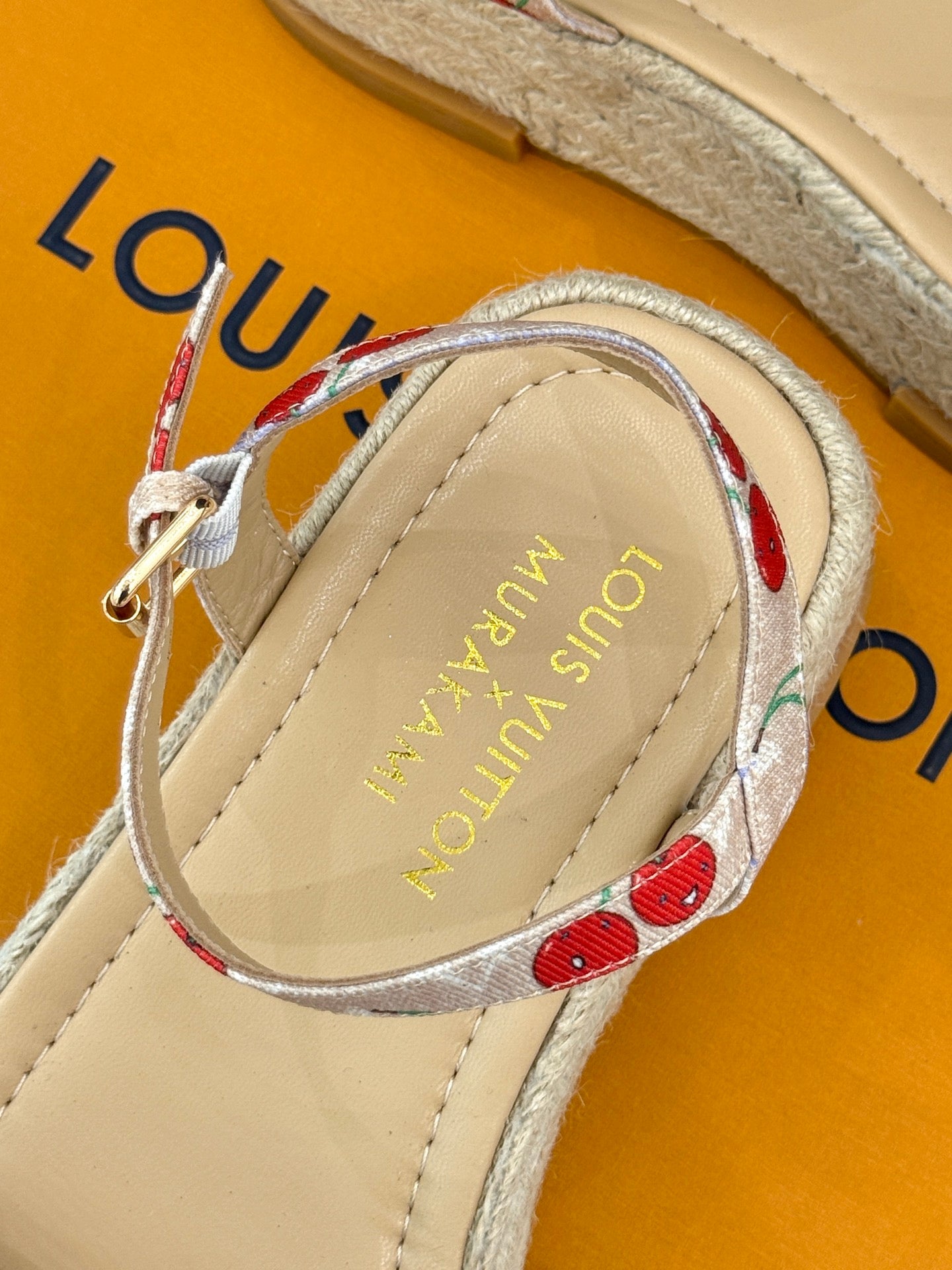 Espadrille sandal close-up of cherry-pattern ankle strap and gold-toned buckle