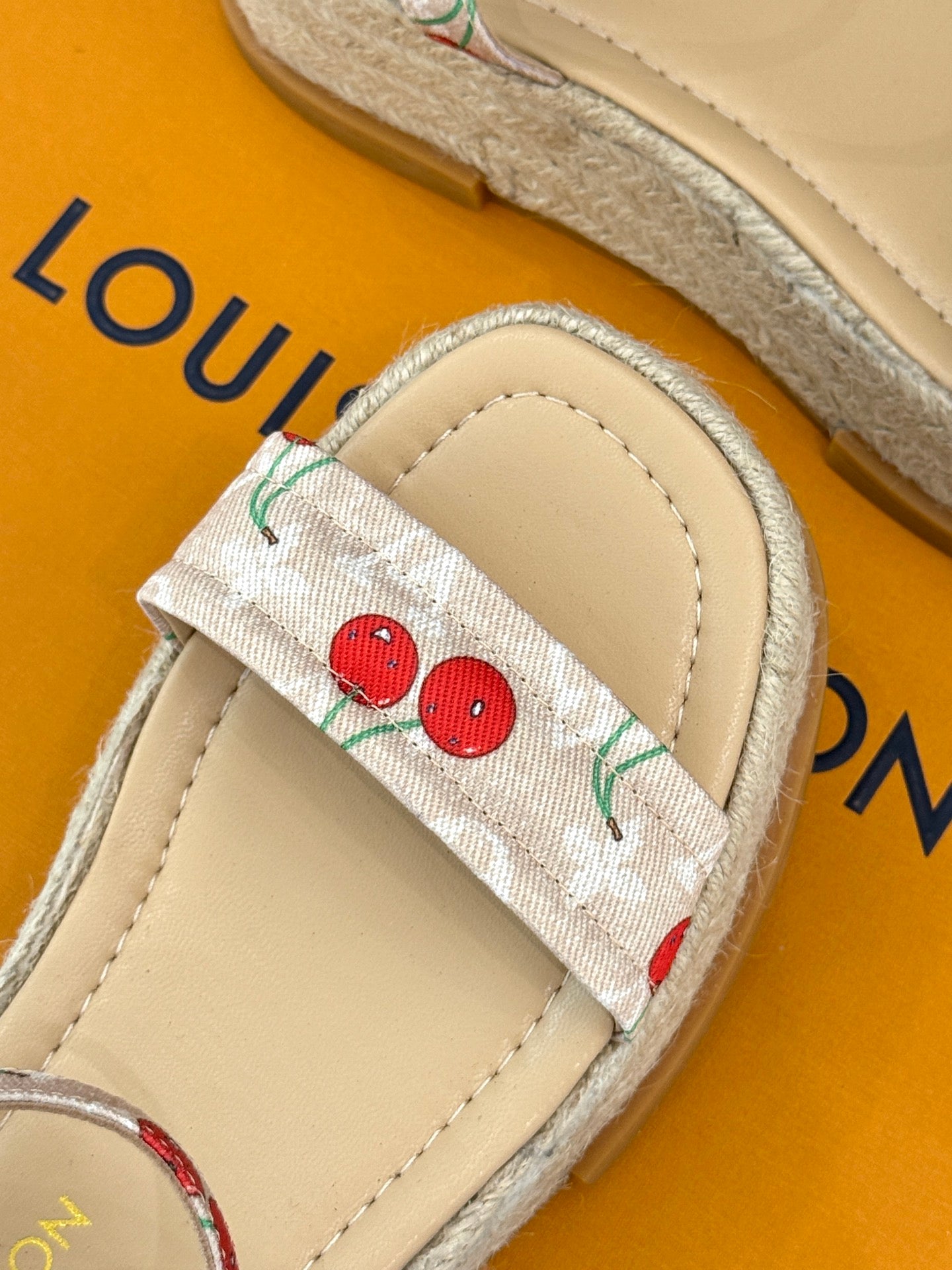 Espadrille sandal close-up: cherry print fabric strap with beige leather lining