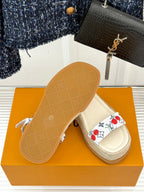 Espadrille sandal on box: beige rubber sole and white cherry-print strap.
