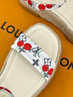 Espadrille sandal strap close-up with red cherry print on white fabric.