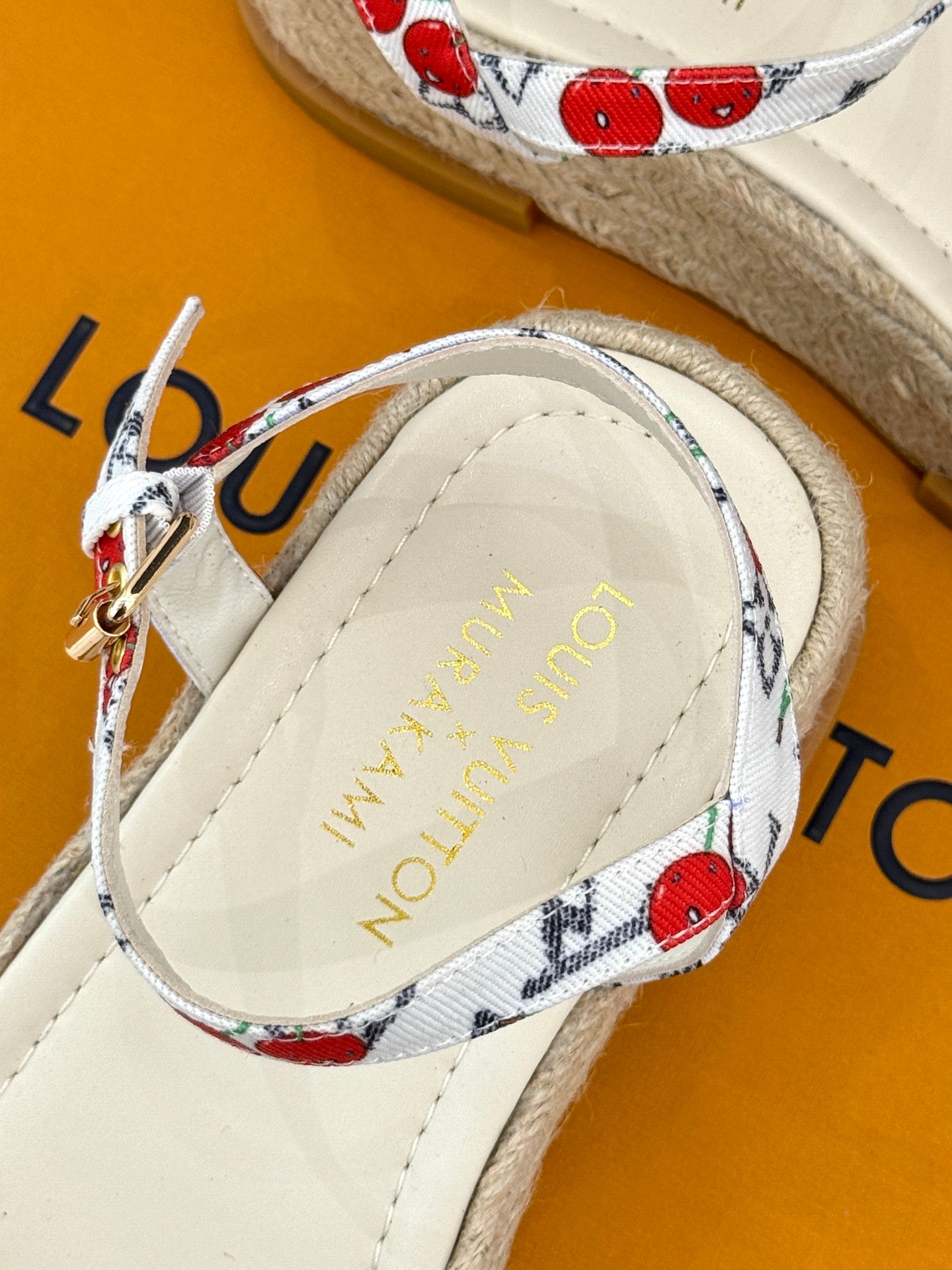 Espadrille sandal insole close-up with gold logo on tan lining.