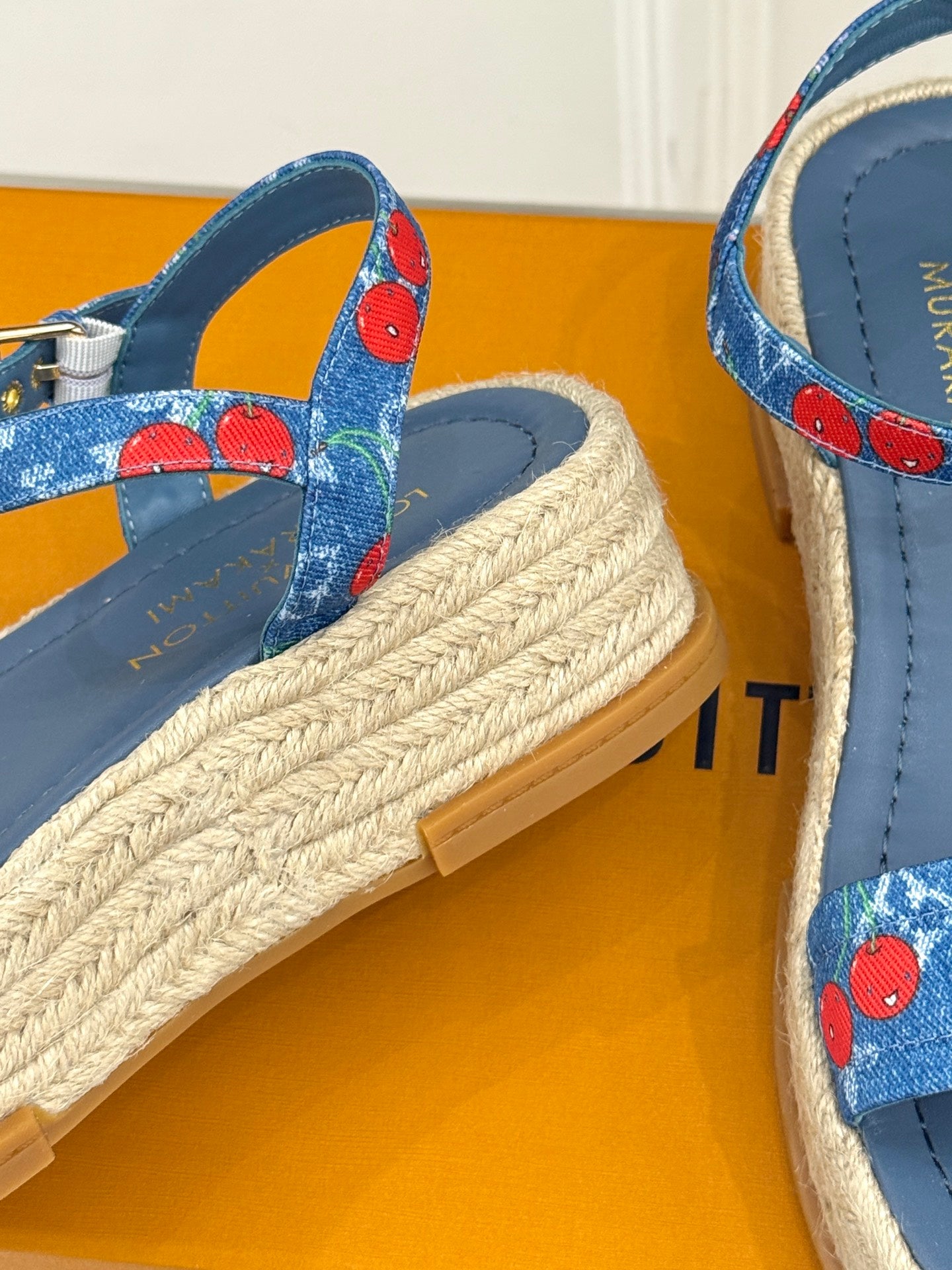 Close-up of blue espadrille wedge sandals with cherry-print side straps