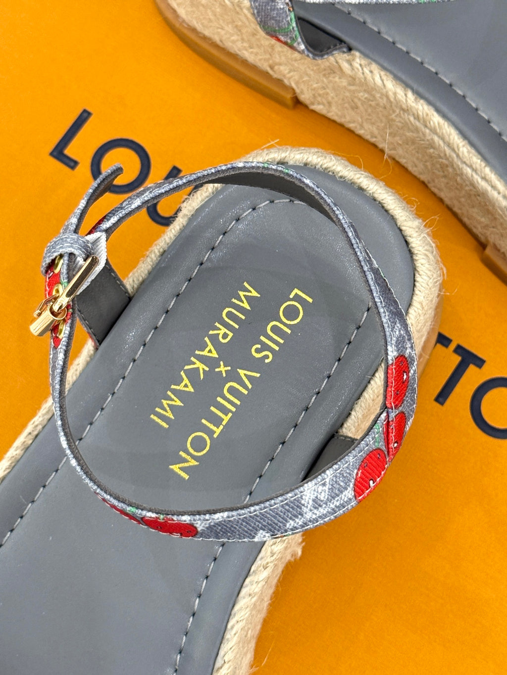 Close-up of grey espadrille sandal with cherry-print strap and gold-tone buckle