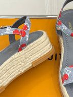 Close-up of grey espadrille sandal with cherry-print strap and woven platform