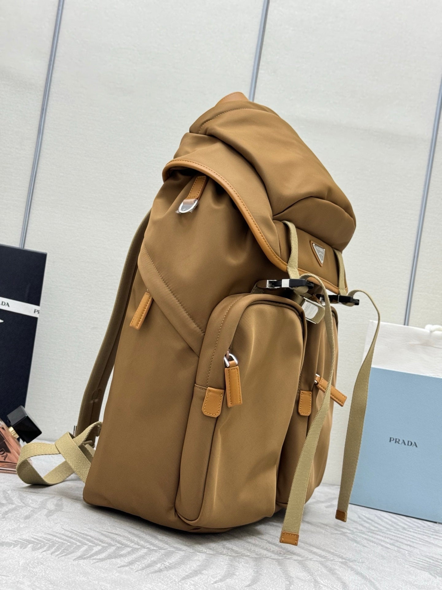 Prada tan backpack side view with flap, front compartments, and silver hardware