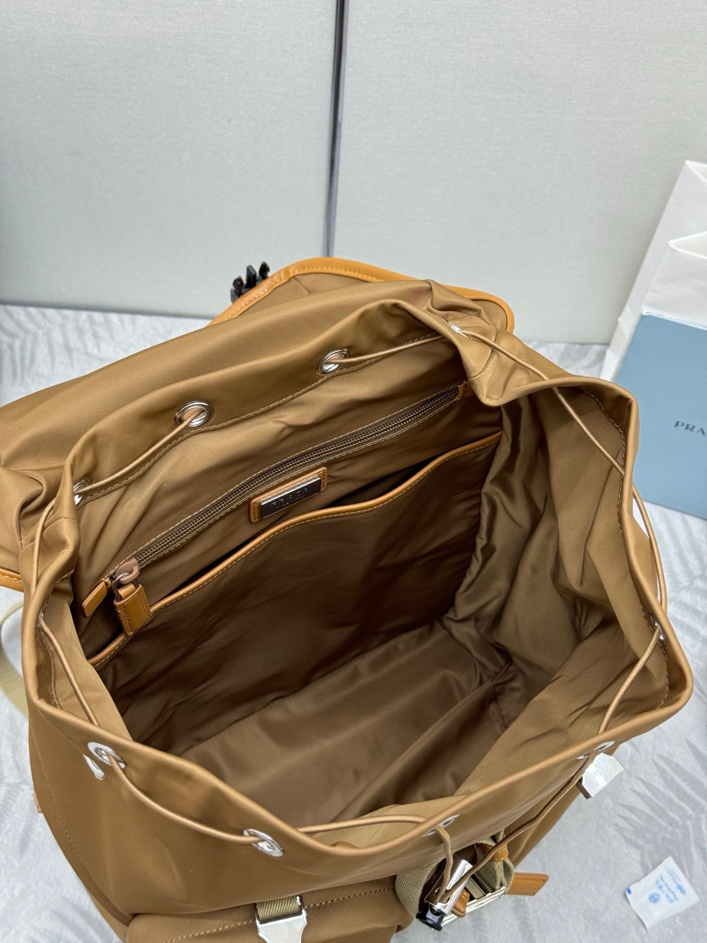 Prada tan backpack interior view with open top compartment and front zipper pocket