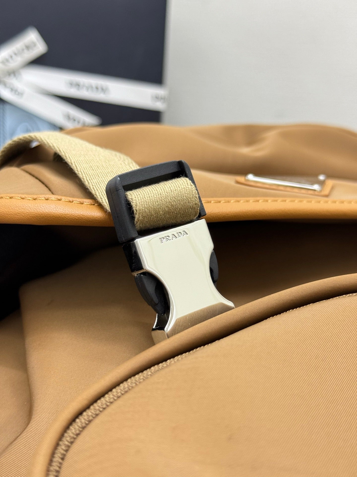 Prada tan backpack close-up of strap buckle and silver hardware with logo detail