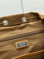 Prada tan backpack close-up of grommet detail, zipper, and logo label on flap