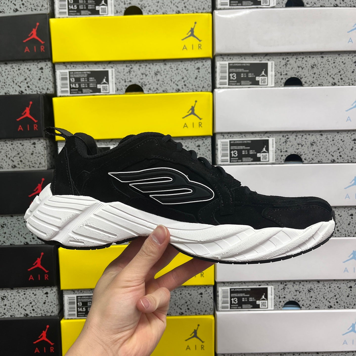Black suede lace-up sneaker with white sole and wing-style side logo