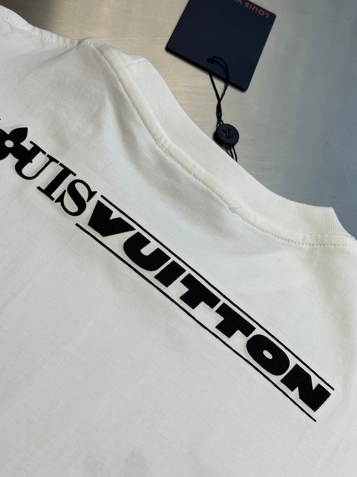 White Louis Vuitton T-shirt with large black “Louis Vuitton” chest logo