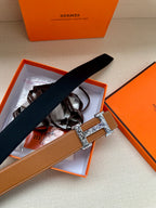 Tan-brown leather belt with silver H buckle and black ribbon