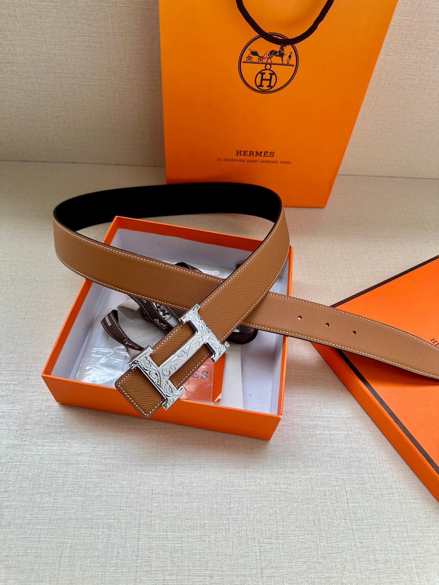 Tan-brown leather belt with silver H buckle, shown with gift box