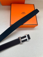 Dark navy leather belt laid diagonally with silver-tone buckle and engraved plate.