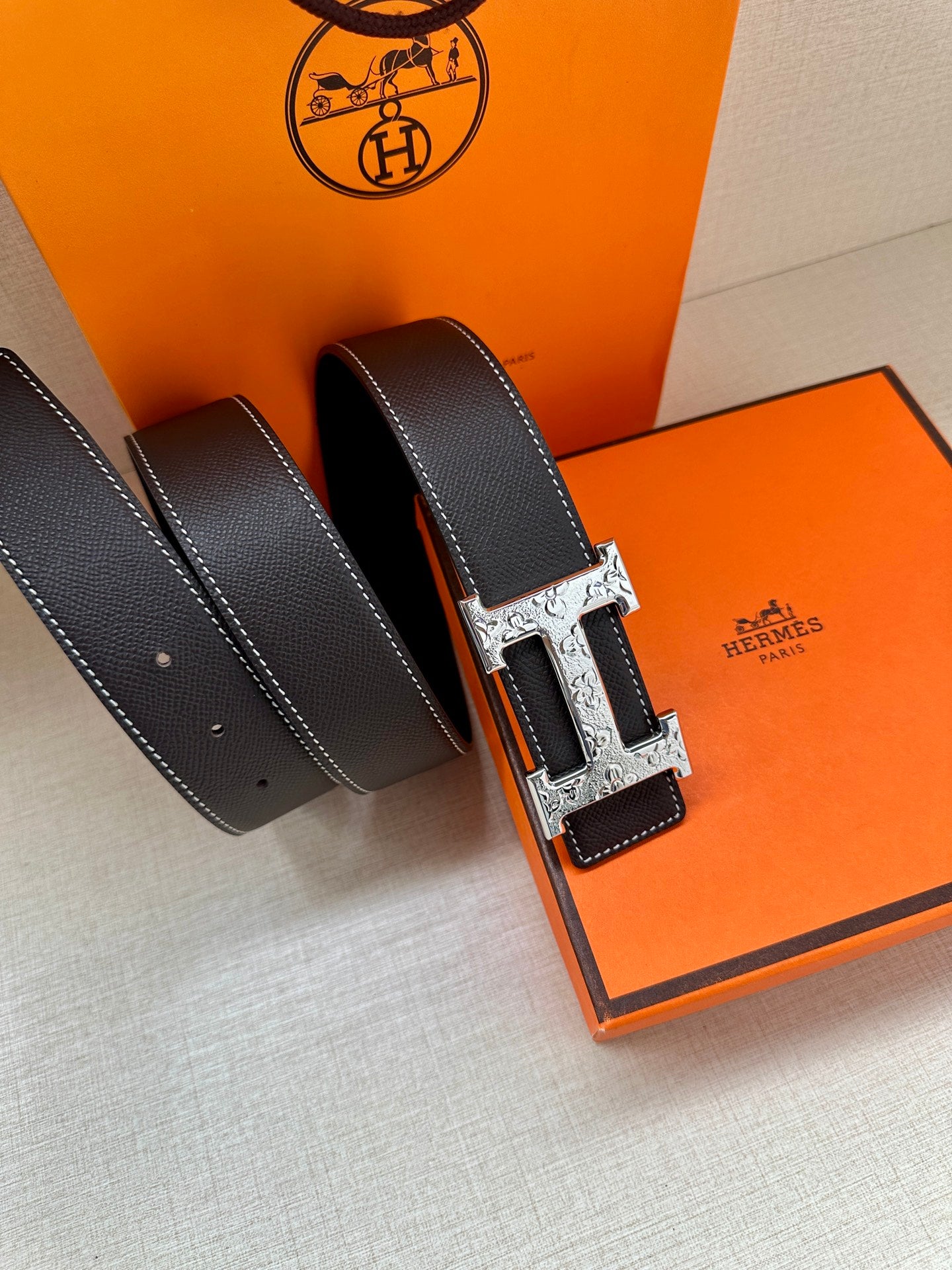 Dark navy leather belt with adjustable holes and silver-tone H buckle.