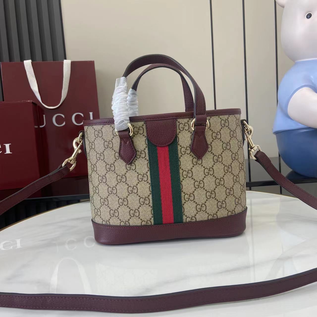 Gucci handbag with GG canvas front, burgundy base, green/red stripe, single shoulder strap.