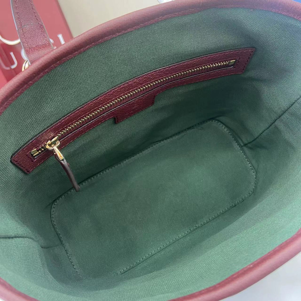 Gucci bag interior with green fabric lining and burgundy zipper pocket.