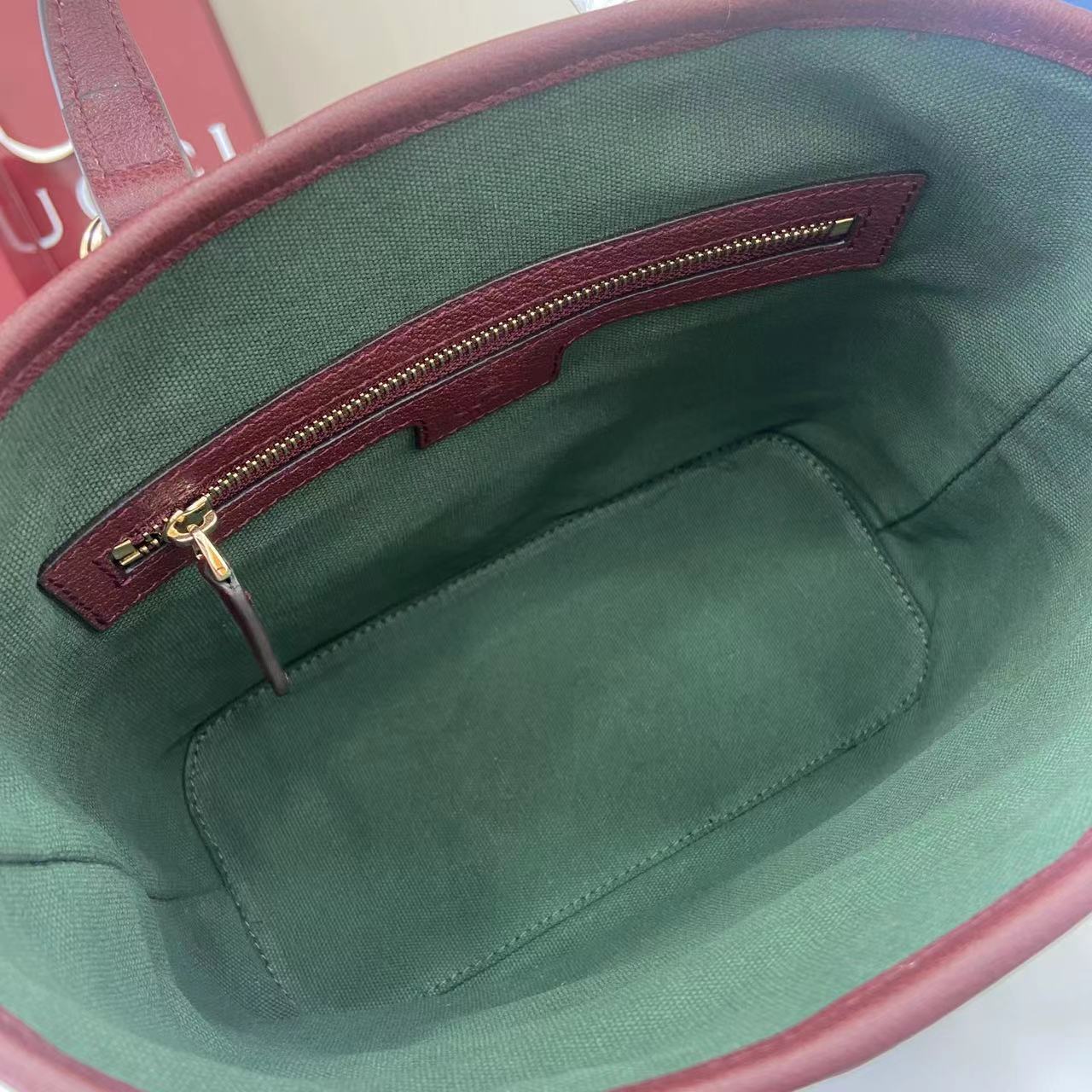 Gucci bag interior with green fabric lining and burgundy zipper pocket.