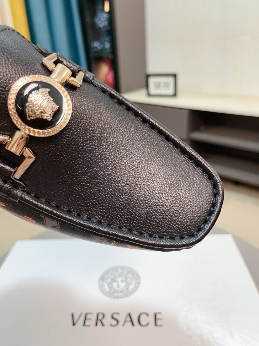 Close-up dark leather loafer toe with gold-tone emblem buckle detail
