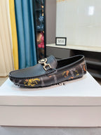 Dark luxury loafer with gold-toned buckle and patterned strap detail