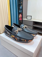 Dark luxury loafers with gold-tone buckles and colorful patterned trim on box