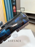 Dark blue patterned loafer with gold clasp and blue floral accents on side