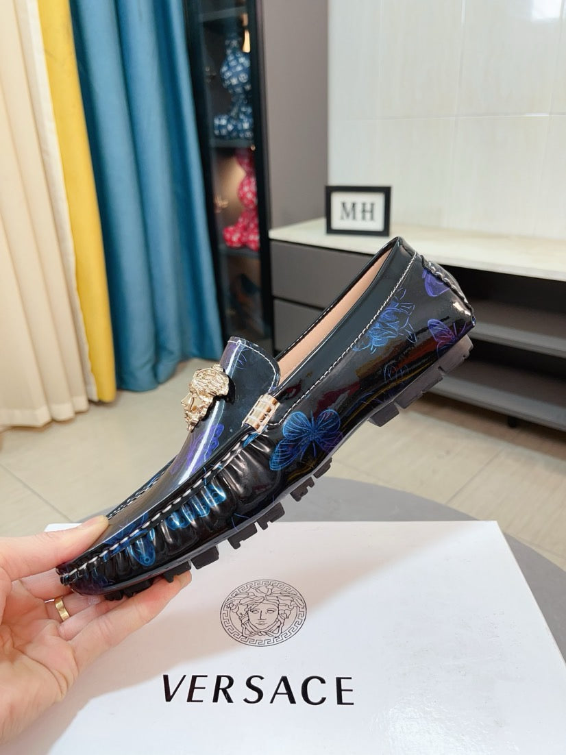 Dark blue patterned loafer with gold lion emblem and bow-like accent on top