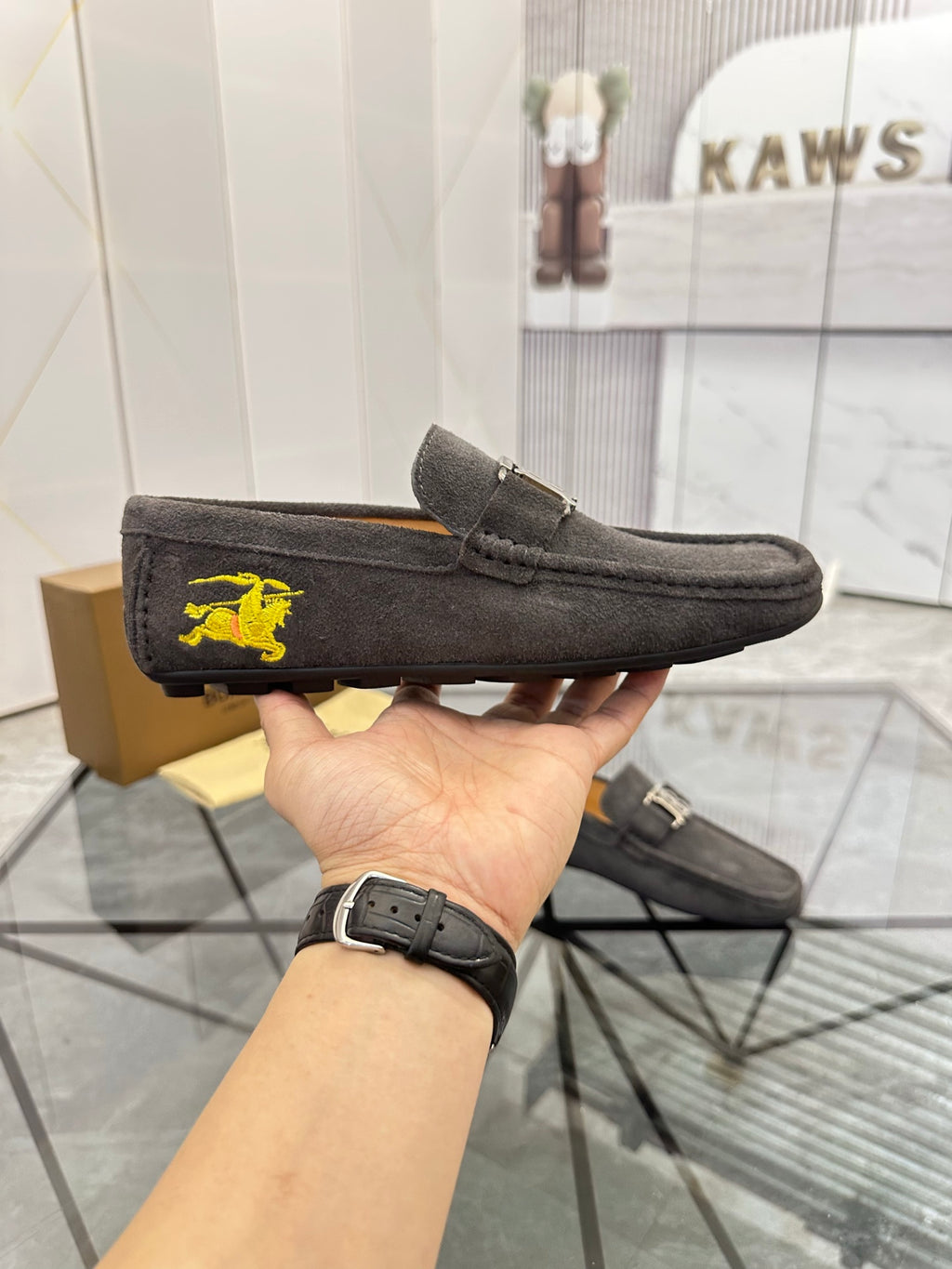 Dark gray suede loafers with yellow horse emblem on side and matching buckle