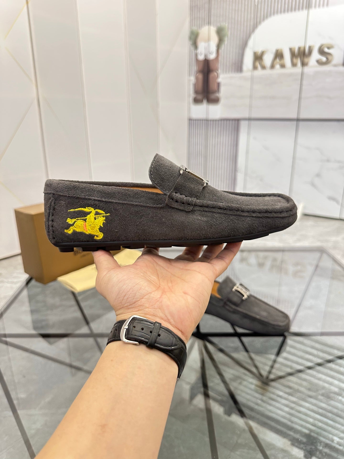 Dark gray suede loafers with yellow horse emblem on side and matching buckle