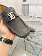 Close-up of dark gray suede loafer with gold-tone B buckle on strap