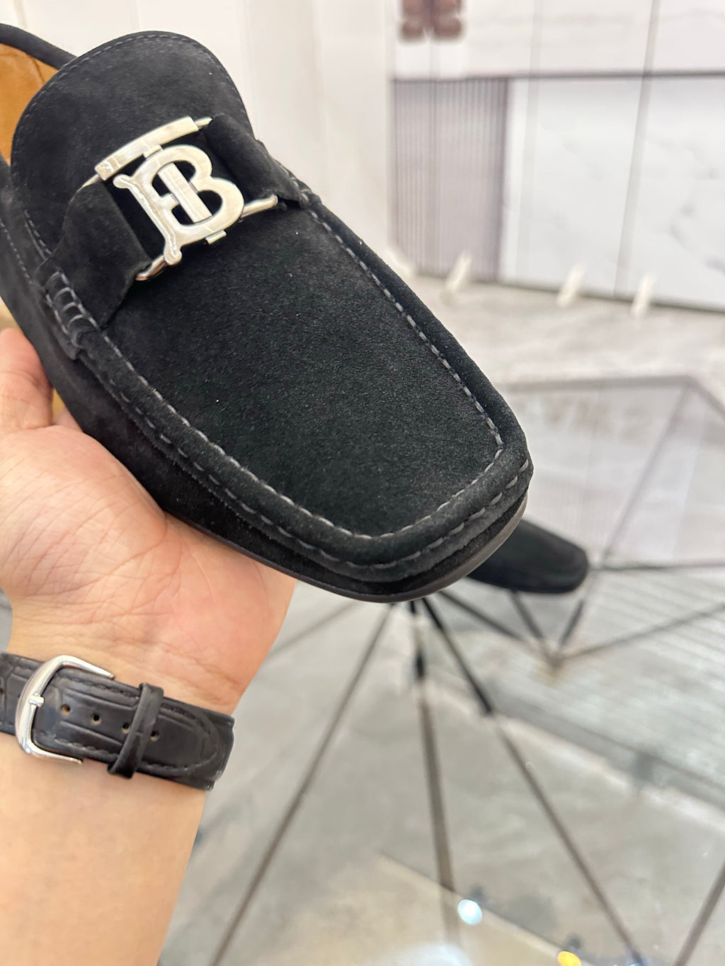 Burberry black loafer close-up with gold-tone “B” buckle and stitched trim