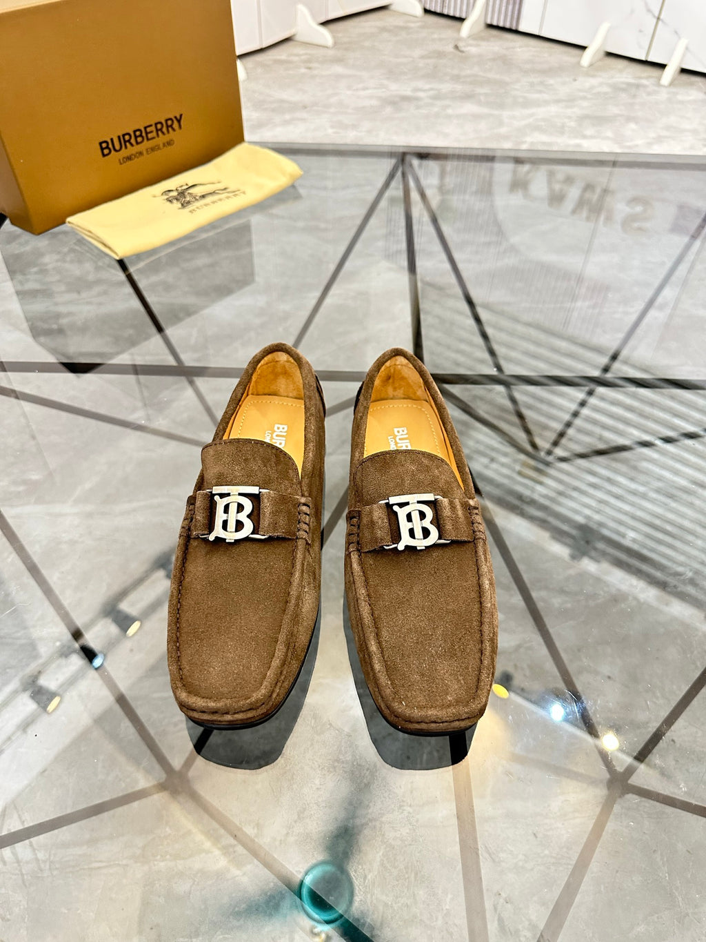Pair of brown suede loafers with B logo hardware on the front, slip-on style.