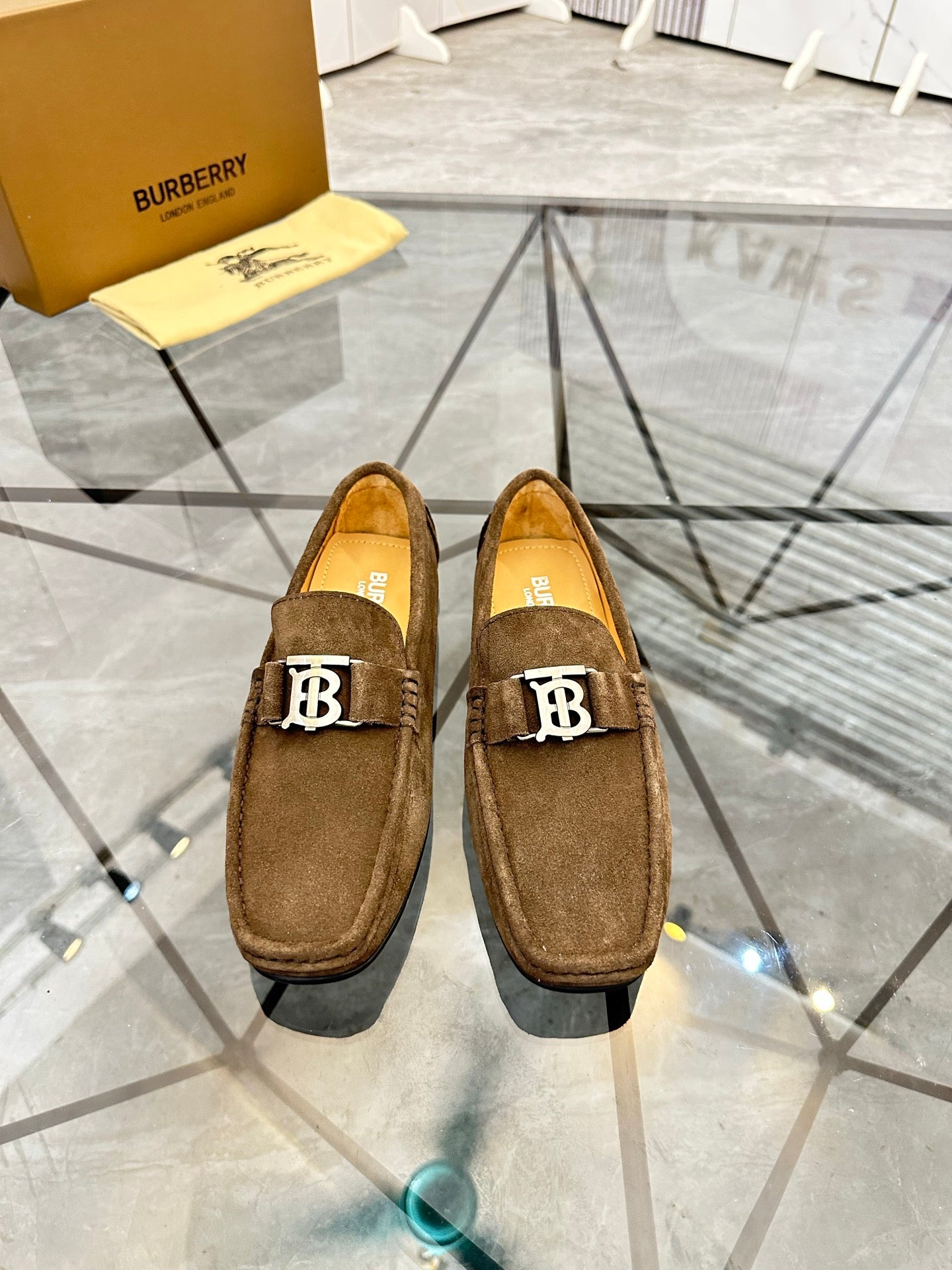 Pair of brown suede loafers with B logo hardware on the front, slip-on style.