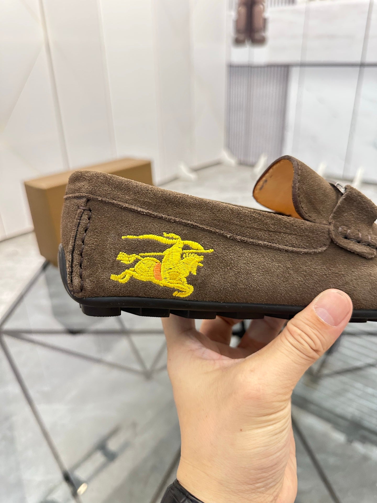 Brown suede loafer with yellow horse embroidery on the side and slip-on tongue detail.
