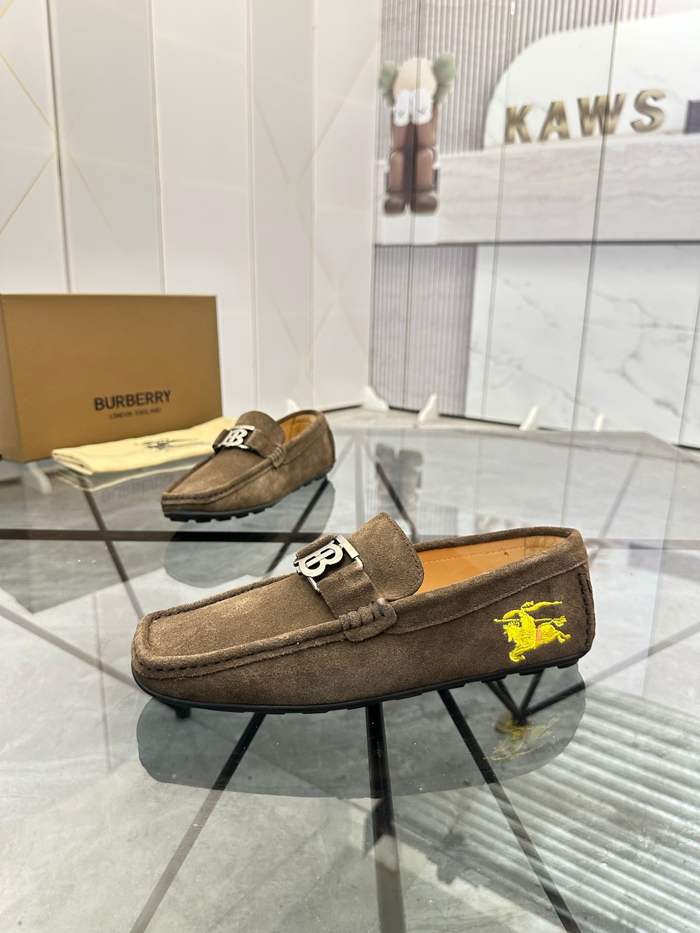Brown suede loafer with slip-on design and yellow horse emblem on the side.