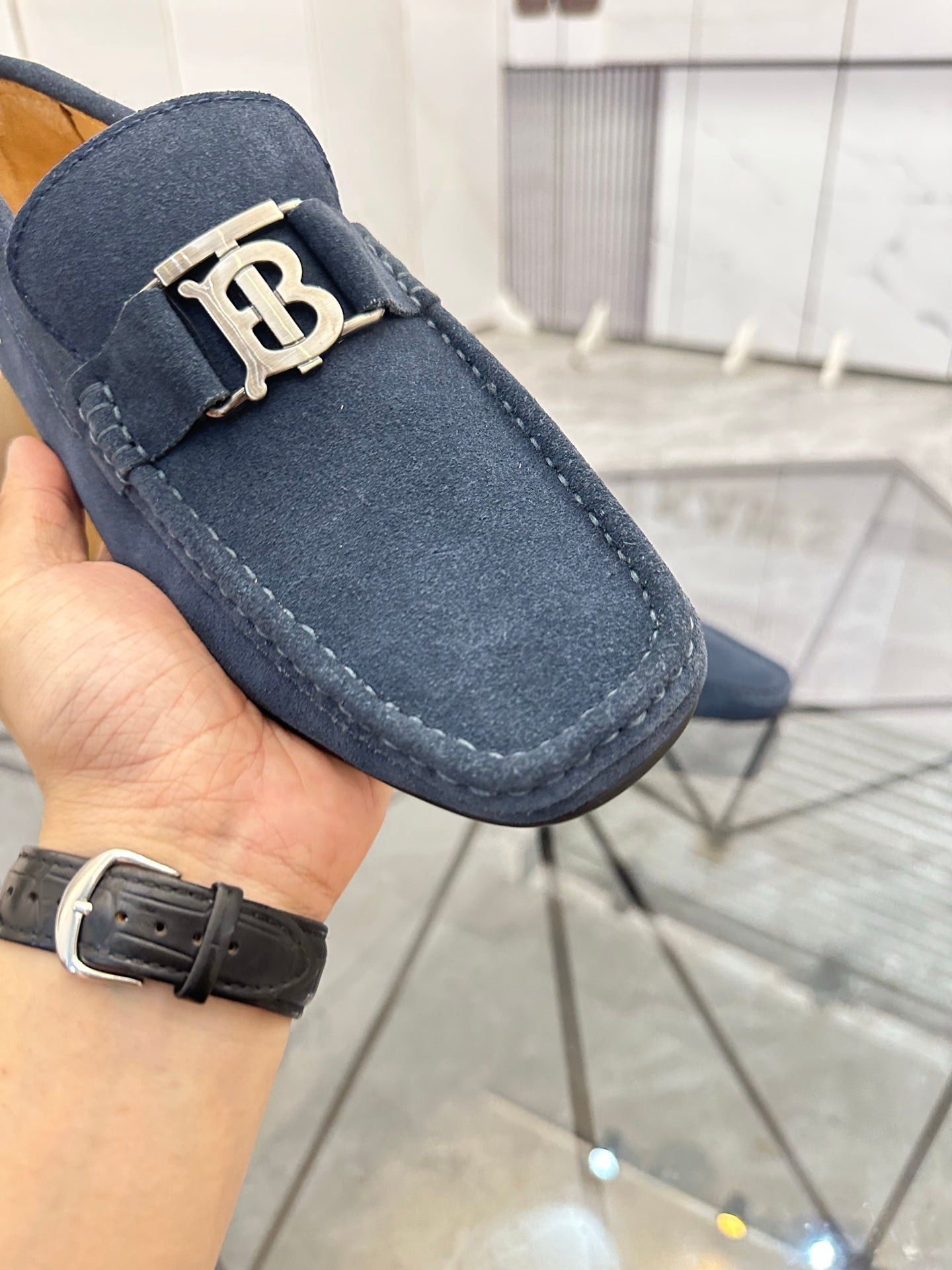 Navy suede loafer close-up with gold-tone B buckle and stitched edge