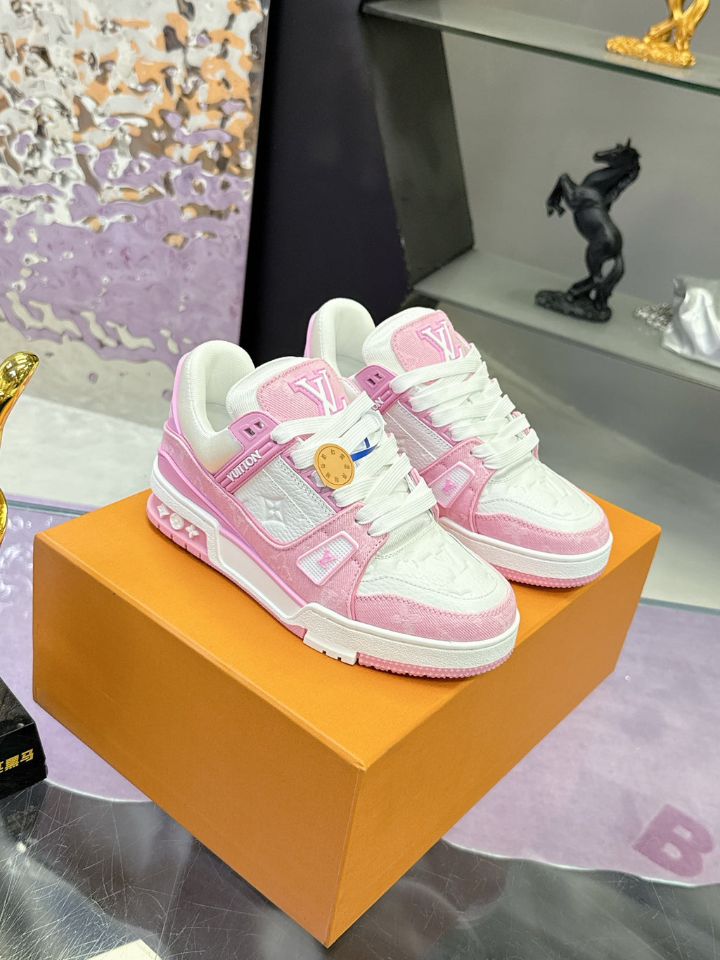 Pink and white Louis Vuitton sneakers on orange box, lace-up style