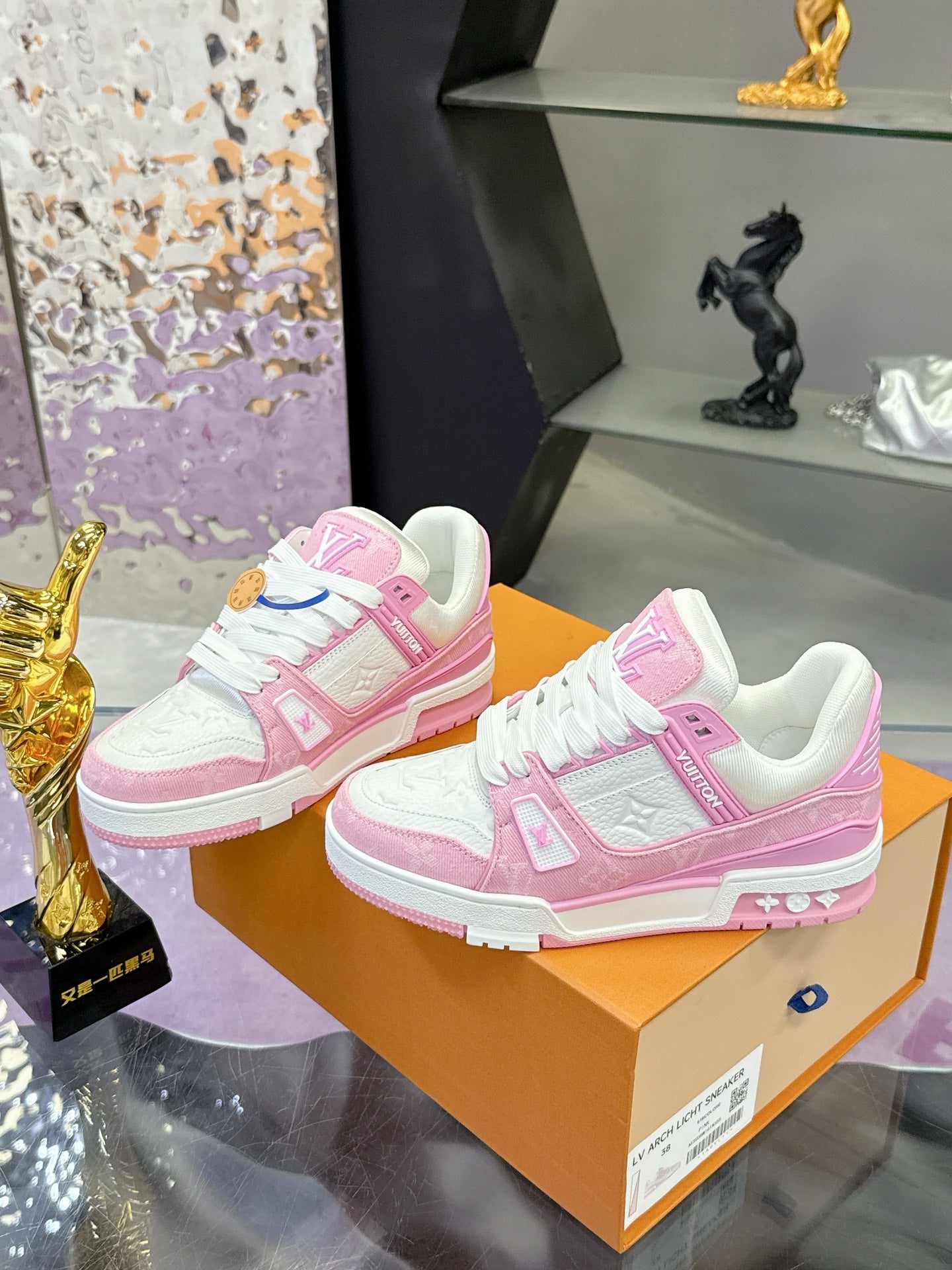 Pink and white Louis Vuitton sneakers on orange box, front and side views