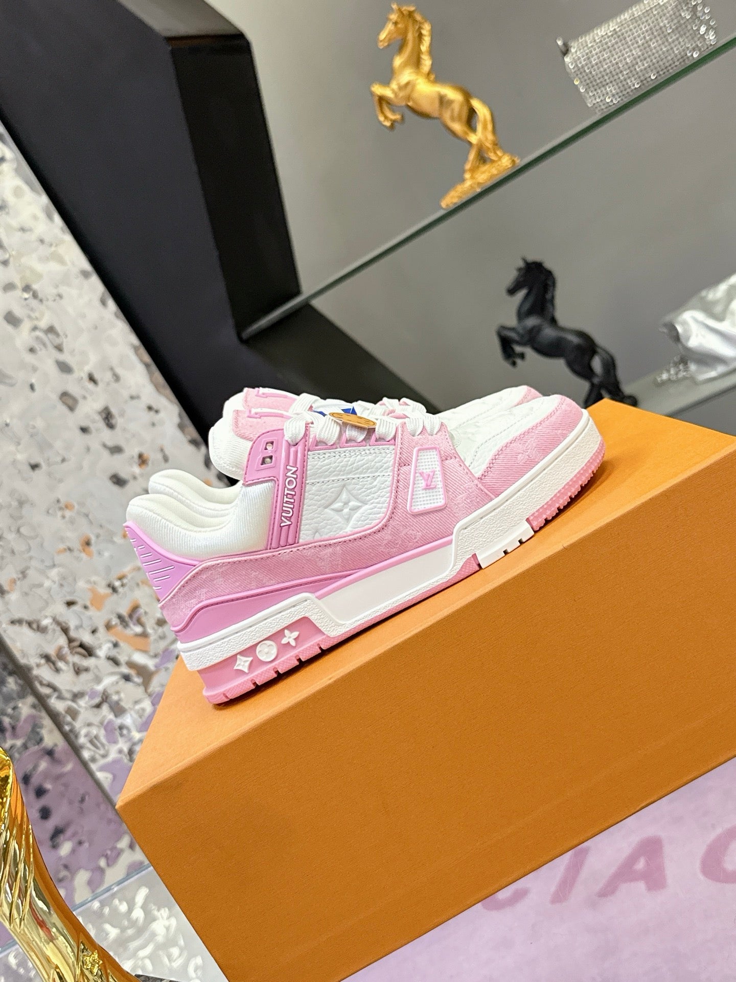 Pink and white Louis Vuitton sneakers on orange display box, side view